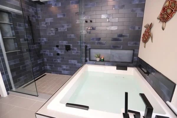 bathroom with large bathtub and dark tile